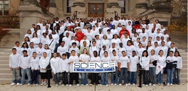 Science Bound students in white shirts holding Science Bound logo sign.