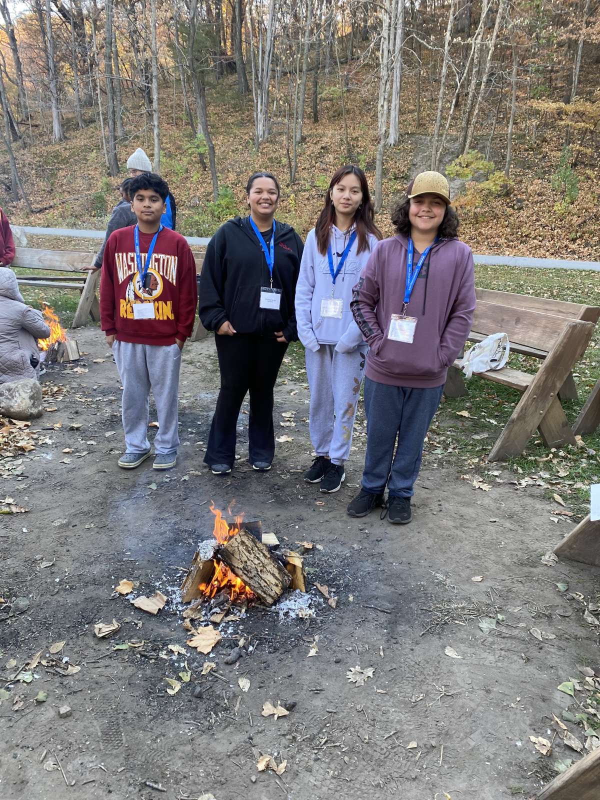 Four Science Bound Students standing behind the fire they built.
